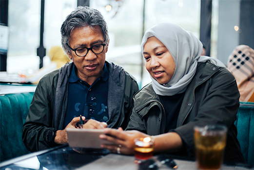 1633163-2EnrollInPlan-521x348 Man and woman sitting looking at smartphone