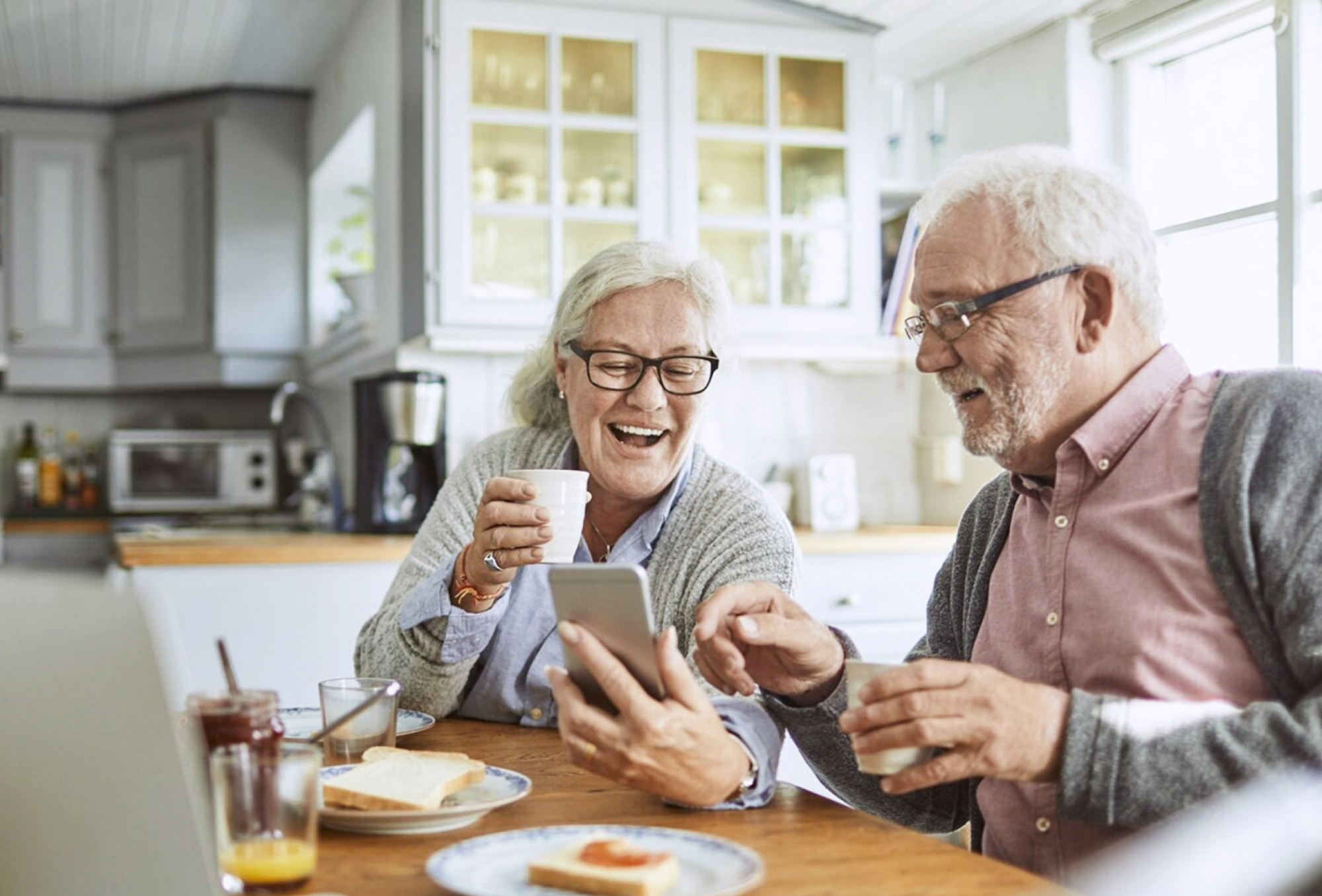 an older couple sitting at a table looking at a smartphone